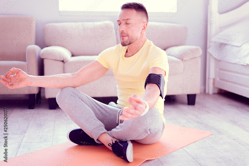 Bearded man feeling relaxed and relieved while meditating in the morning Bearded man feeling relaxed and relieved while meditating in the morning