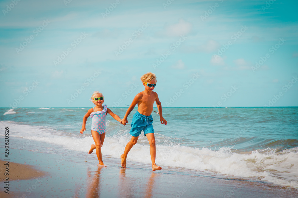 happy kids- boy and girl -running on beach