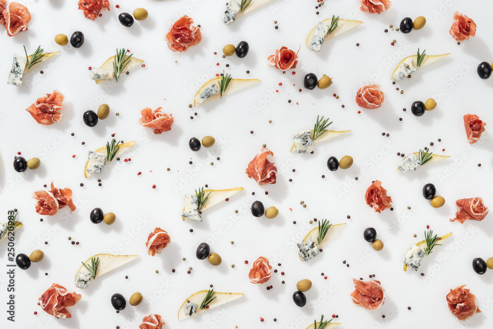 flat lay of sliced pears with blue cheese and rosemary twigs near black and green olives and tasty prosciutto on white background flat lay of sliced pears with blue cheese and rosemary twigs near black and green olives and tasty prosciutto on white background