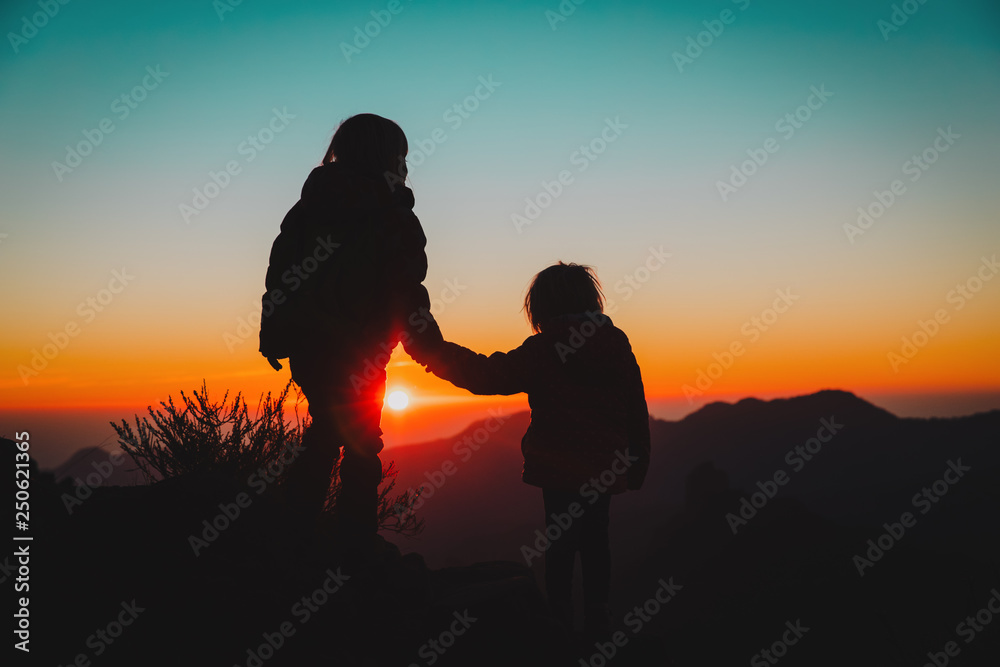 Silhouettes of girls hiking at sunset mountains, kids travel in nature