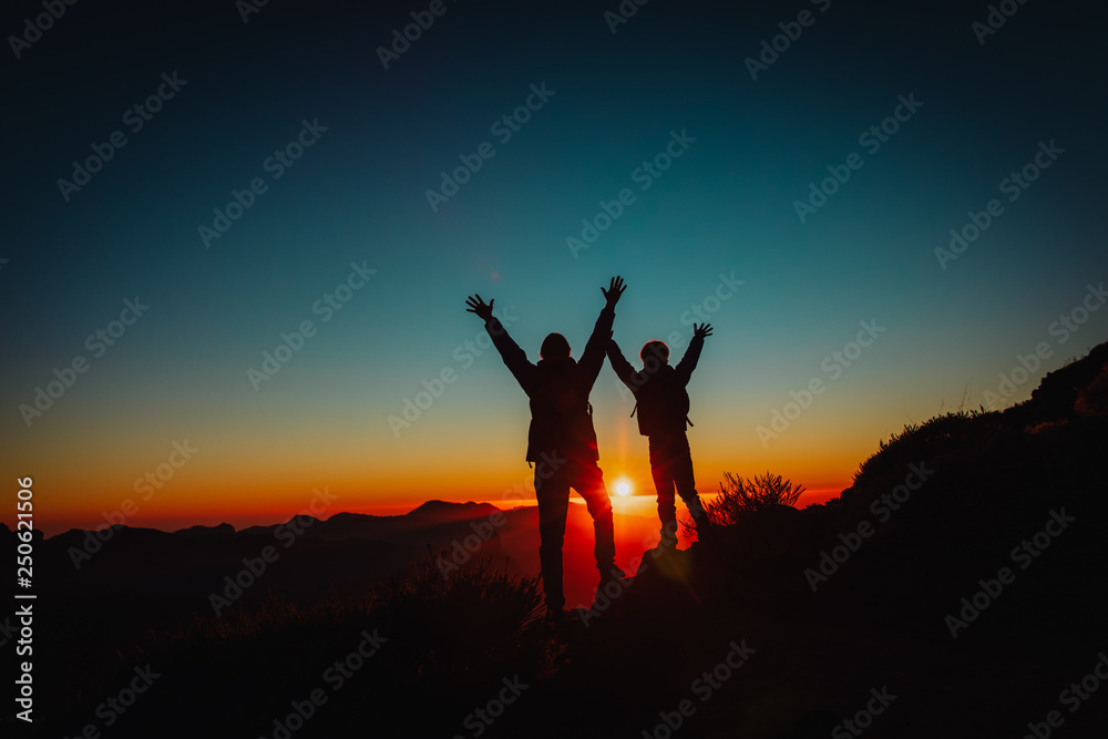 Silhouettes of father and son hiking at sunset, family travel in nature