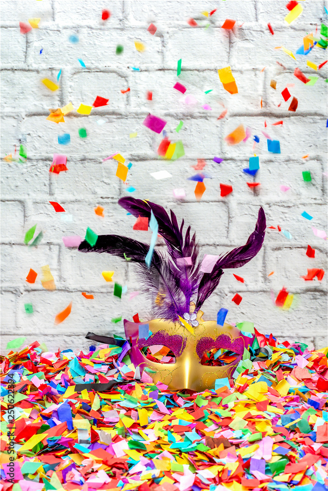 Carnival mask with violet feathers with confetti falling