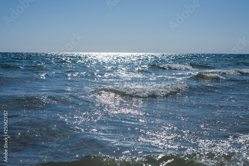 Blue summer sea waves with sparkling sunlight on it.