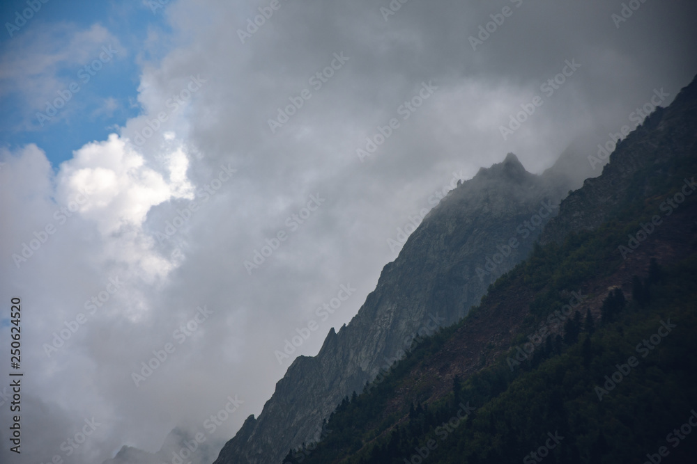 Peaks of Dombai mountains in summer rain clouds