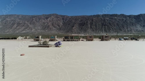 Aerial drone scene of barreal desert at aimogasta, la rioja, argentina. Camera moving forwards and over abandoned small adobe houses and racing cart. The andes mountains on background. photo