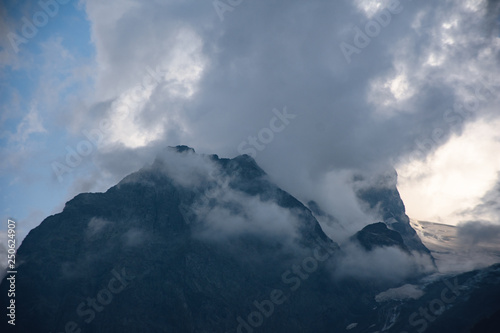 Peaks of Dombai mountains in summer rain clouds