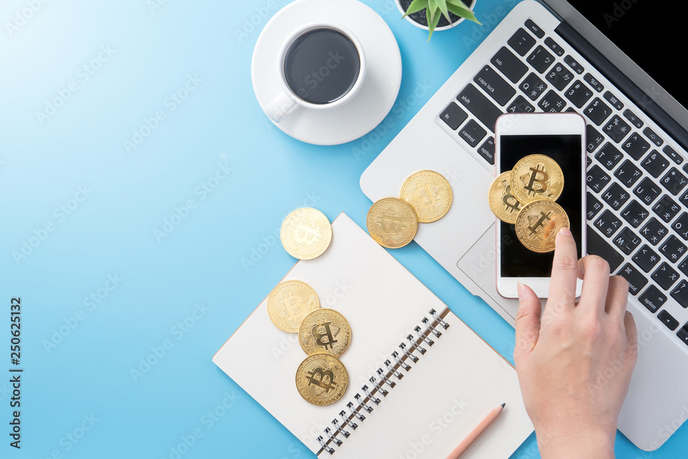 A woman is accounting the money concept isolated on clean blue office working desk with bitcoin and coffee cup, workspace design, mock up, top view, flat lay, copy space, close up