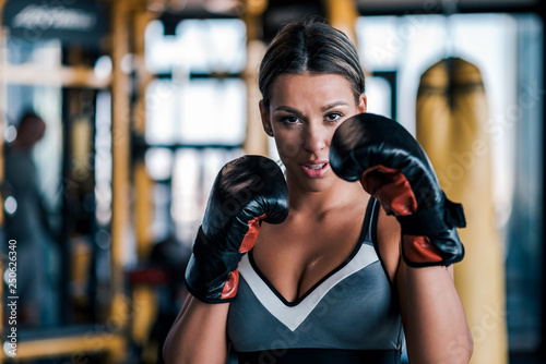 Close-up of a young fit woman in boxing gloves, front view. © bnenin