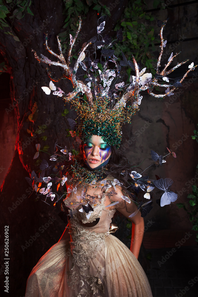 natural nymph with horns like branches of a tree and butterflies circling  around. Fantasy style costume Photos | Adobe Stock