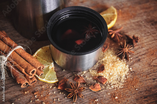 Freshly homemade mulled wine in a bowl with fragrant species, citrus fruits, lemon on a wooden rusric board photo