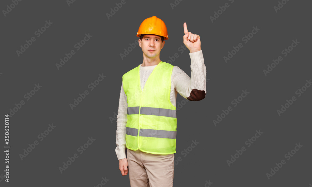 The man the builder in a helmet and a vest points a finger up The man the builder in a helmet and a vest points a finger up