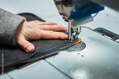 The hand of a designer who stitching a fragment of a bag