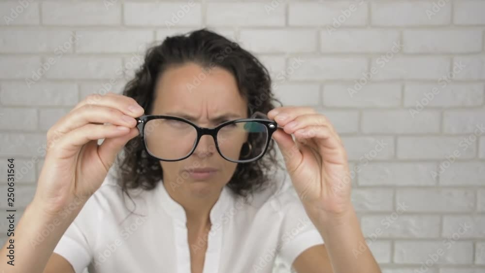 Happy woman puts on glasses. A woman with poor eyesight puts on glasses. Happy woman puts on glasses. A woman with poor eyesight puts on glasses.