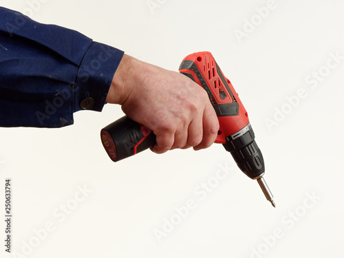 man in workwear holds a drill tool on white background.