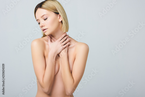 tender naked woman covering breast and posing isolated on grey