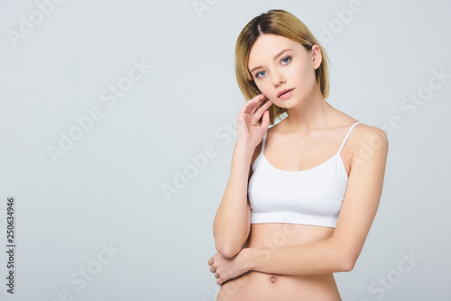 attractive young woman posing in white bra isolated on grey © LIGHTFIELD STUDIOS