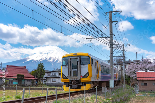 Fujikyu Railway train railroad track with snow covered Mount Fuji ( Mt. Fuji ) background in cherry blossom springtime. Fujiyoshida City, Yamanashi Prefecture, Japan