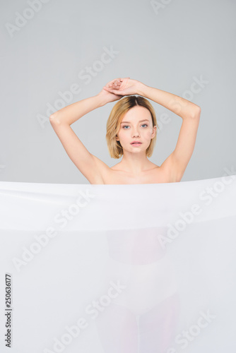 beautiful blonde naked girl posing with white veil  isolated on grey