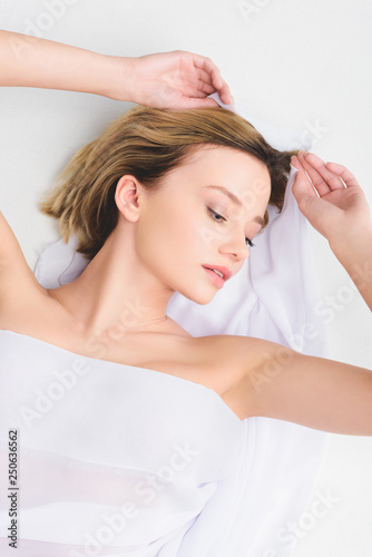 top view of blonde attractive girl lying with white veil, isolated on grey