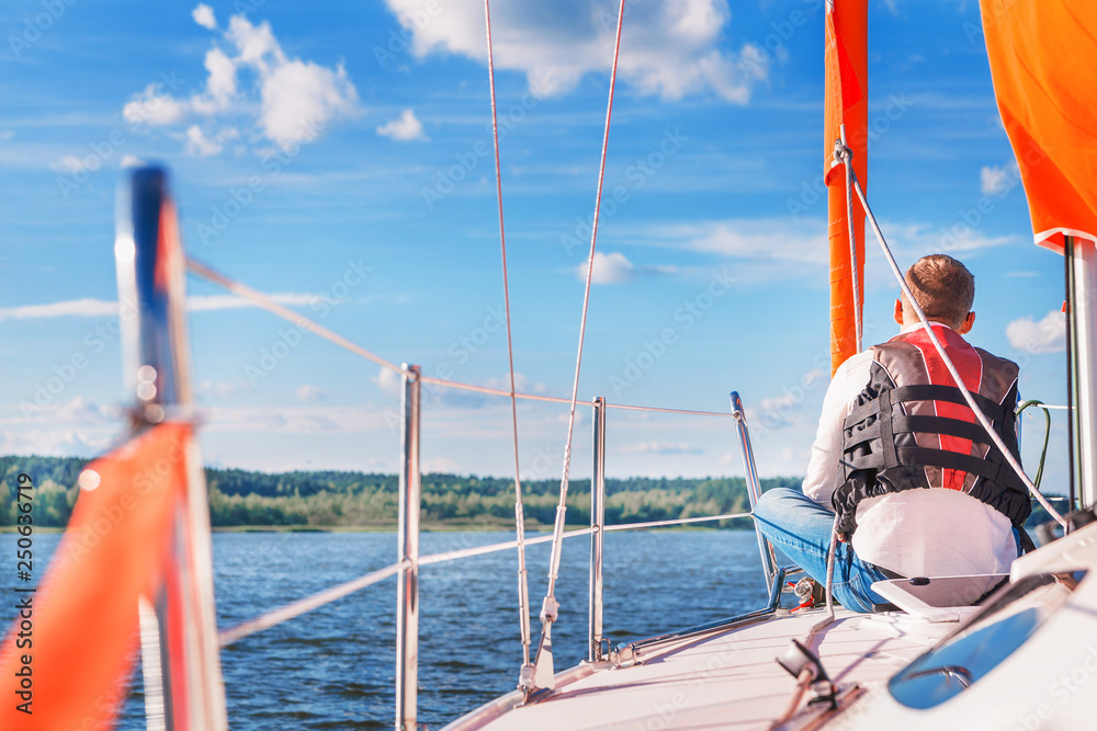 Naklejka premium young man on a boat in a life jacket