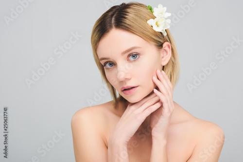 tender blonde girl with freesia flowers in hair, isolated on grey