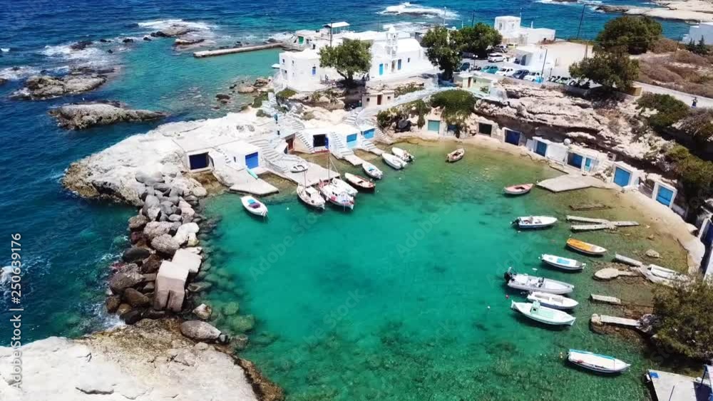 Aerial drone bird's eye view video of picturesque small fishing harbor of Mandrakia with boat houses called syrmata and fishing boats docked on turquoise clear waters, Milos island, Cyclades, Greece Aerial drone bird's eye view video of picturesque small fishing harbor of Mandrakia with boat houses called syrmata and fishing boats docked on turquoise clear waters, Milos island, Cyclades, Greece