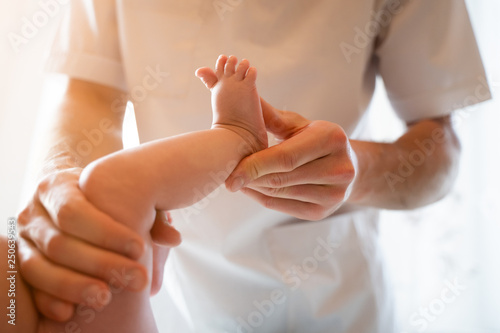 Photo from above of newborn baby and male masseur hands.