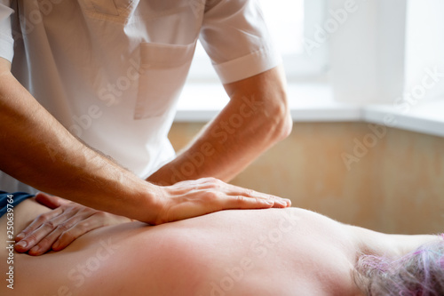 Masseur doing massage of back young girl.