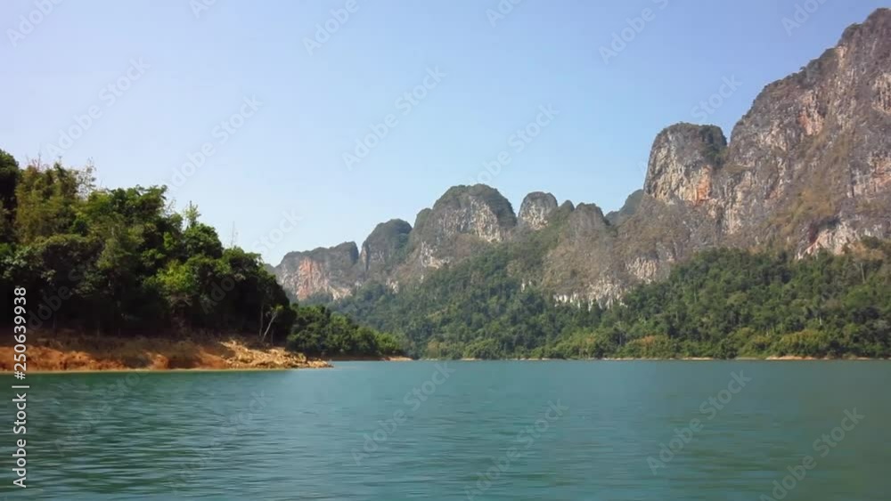 Boat trip on the blue water of Cheo Lan Lake in Thailand among rocks and jungle on a summer day Boat trip on the blue water of Cheo Lan Lake in Thailand among rocks and jungle on a summer day