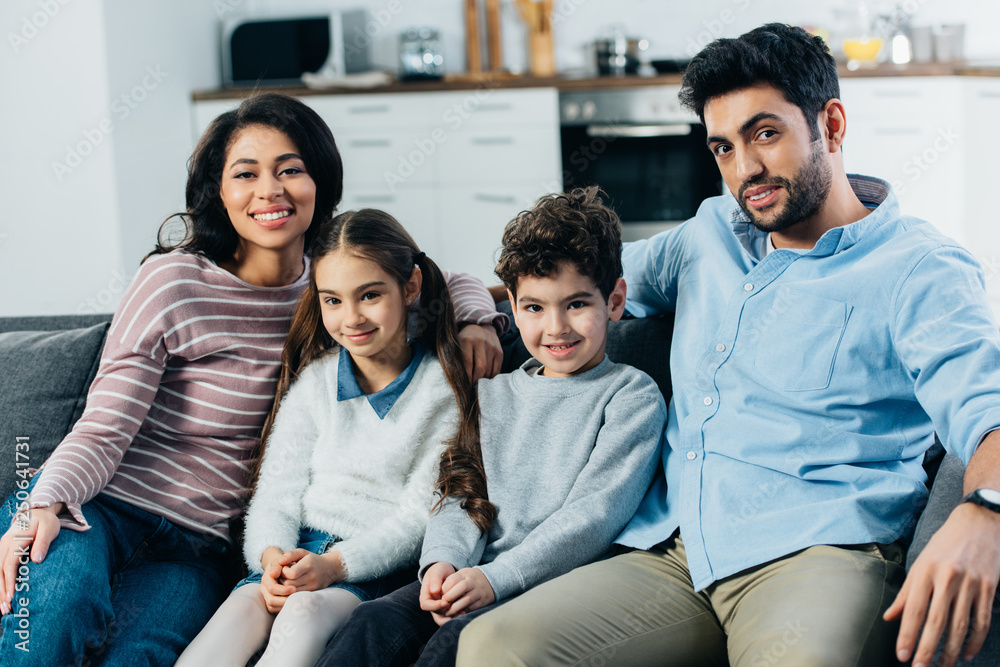 happy hispanic family sitting on sofa and smiling at home