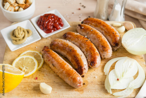 fried sausage, pork sausages with mustard ketchup, onions, lemon on a cutting Board