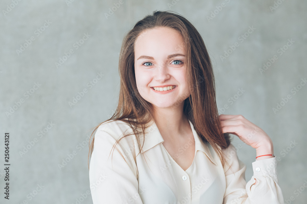 Smiling young woman portrait. Happiness. Attractive content female touching hear. Copy space on grey background. Smiling young woman portrait. Happiness. Attractive content female touching hear. Copy space on grey background.