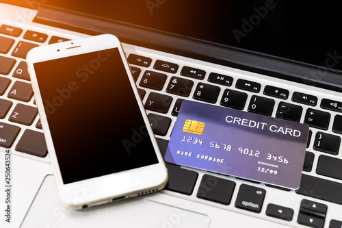 credit card put beside mobile phone on laptop keyboard for preparing to pay with flare