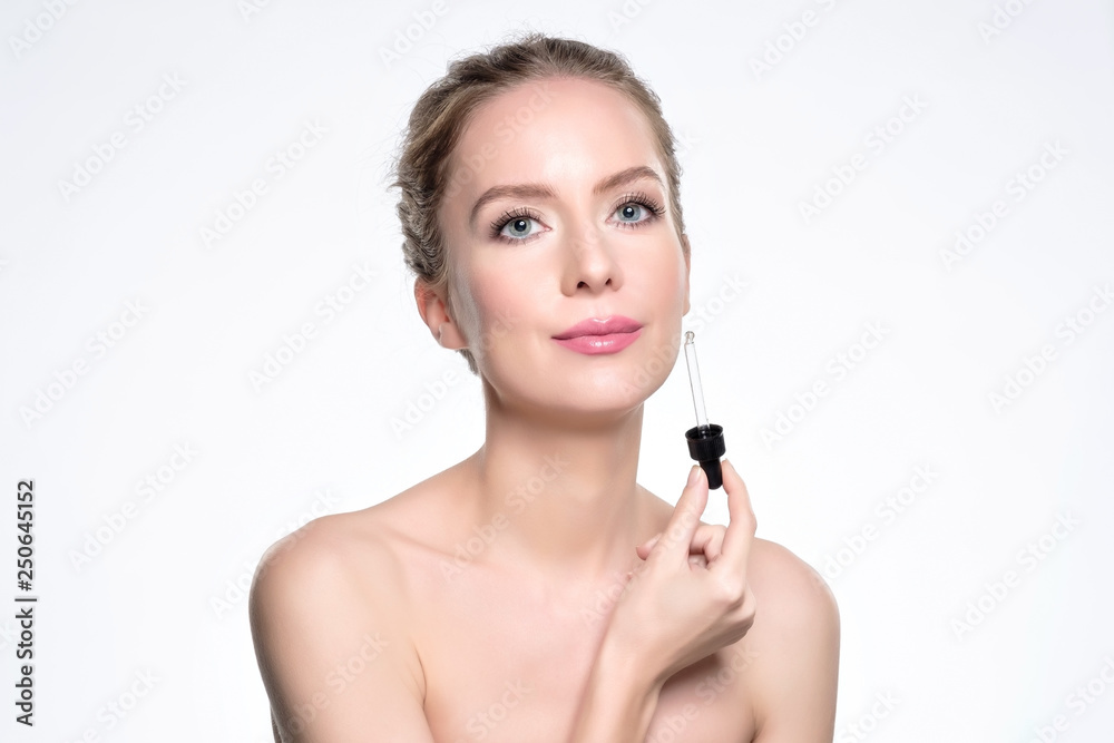 Beautiful model applying a cosmetic skin serum treatment on white