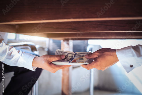 Corruption concept, Businessman taking bribe from man under table. - Image