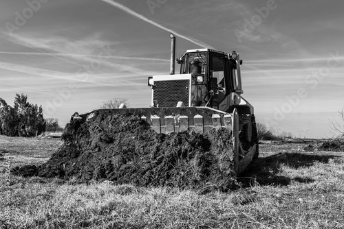 A big yellow bulldozer pushes the ground and makes a new road