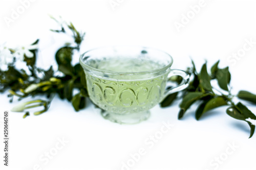 Close up of tea of Indian jasmine flower or juhi or Jasminum Auriculatum isolated on white  in a glass cup with raw flowers.; photo