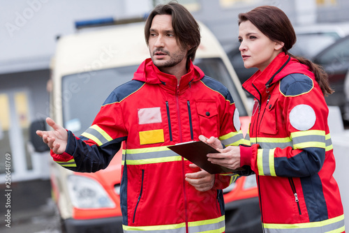 Paramedics in red uniform talking and looking away on street photo