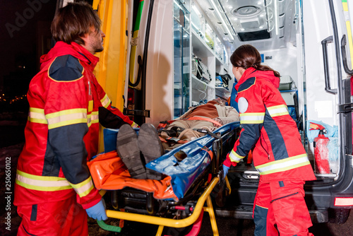 Paramedics transportating patient on gurney in ambulance car photo
