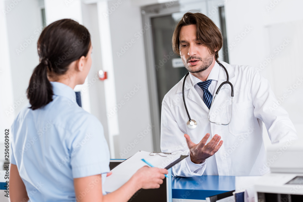 Handsome doctor in white coat talking to nurse Handsome doctor in white coat talking to nurse