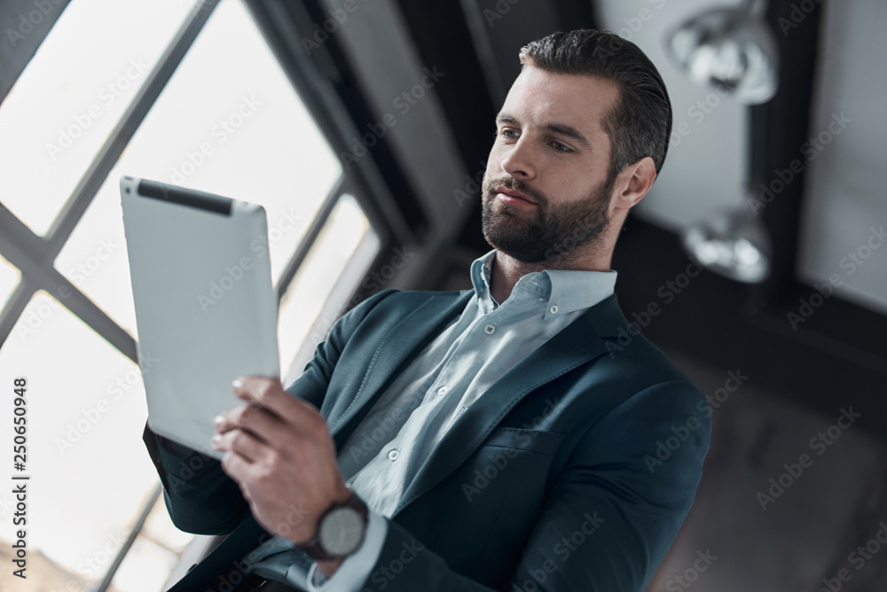 Young stylish businessman leader indoors at office using digital Young stylish businessman leader indoors at office using digital