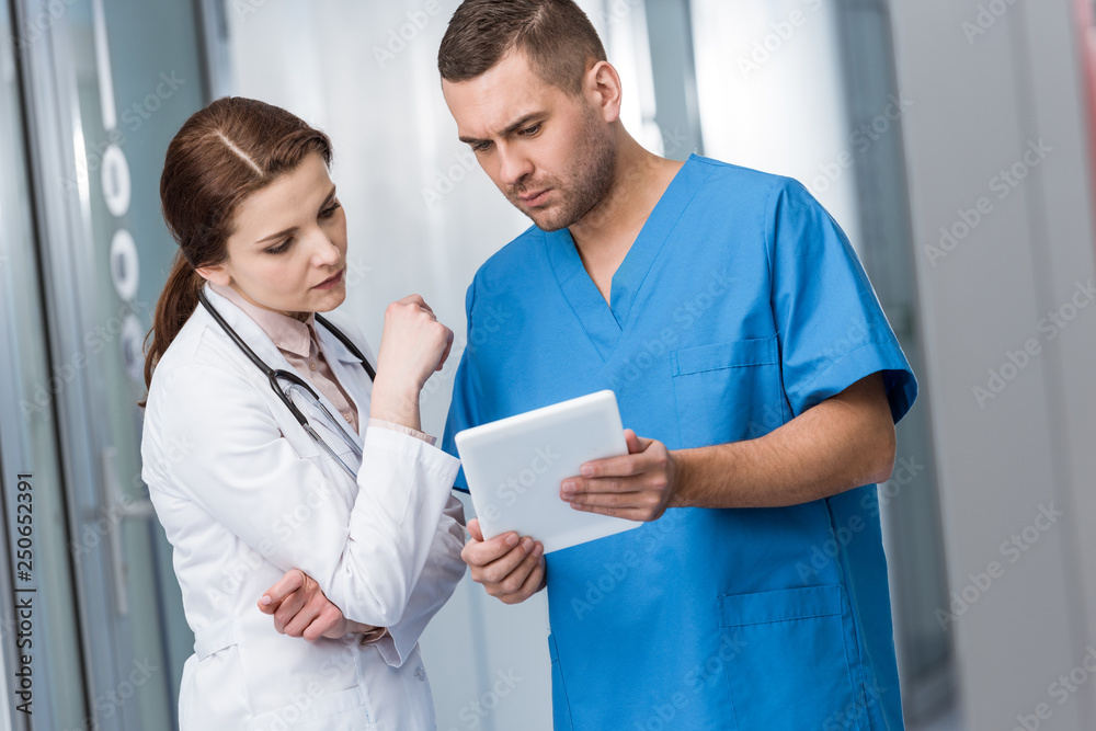 Serious doctors looking at digital tablet together