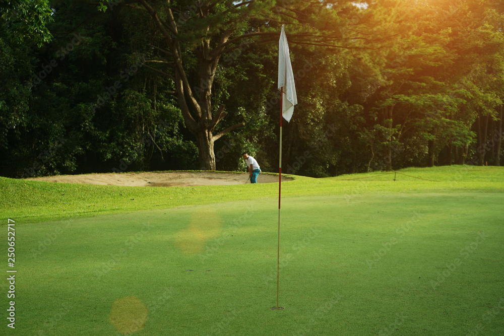 Obraz premium Blurred golfers are playing golf in the evening golf course, on sun set evening time.