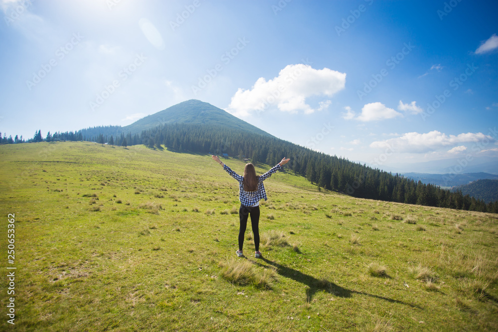 Hiking girl on top of hill with hands up enjoy mountain view.
