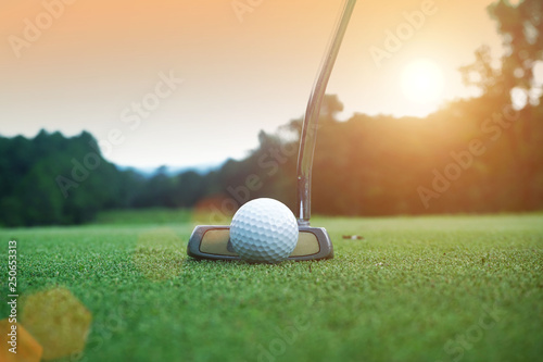 Fotografía golf club and golf ball close up in grass field with sunset