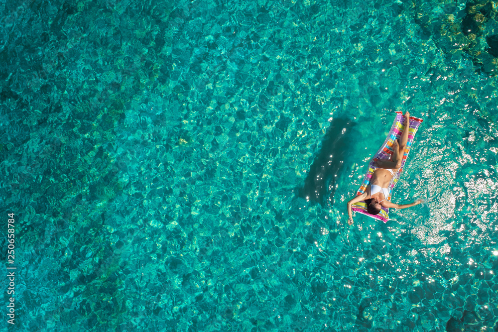 Aerial view of young woman swimming on the pink inflatable mattr.