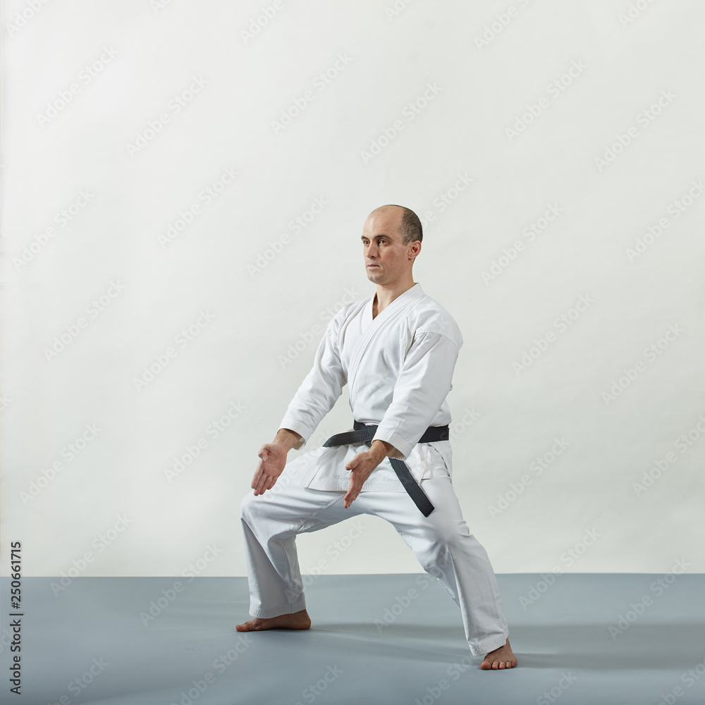 Athlete in karategi doing formal exercises on gray cover Athlete in karategi doing formal exercises on gray cover