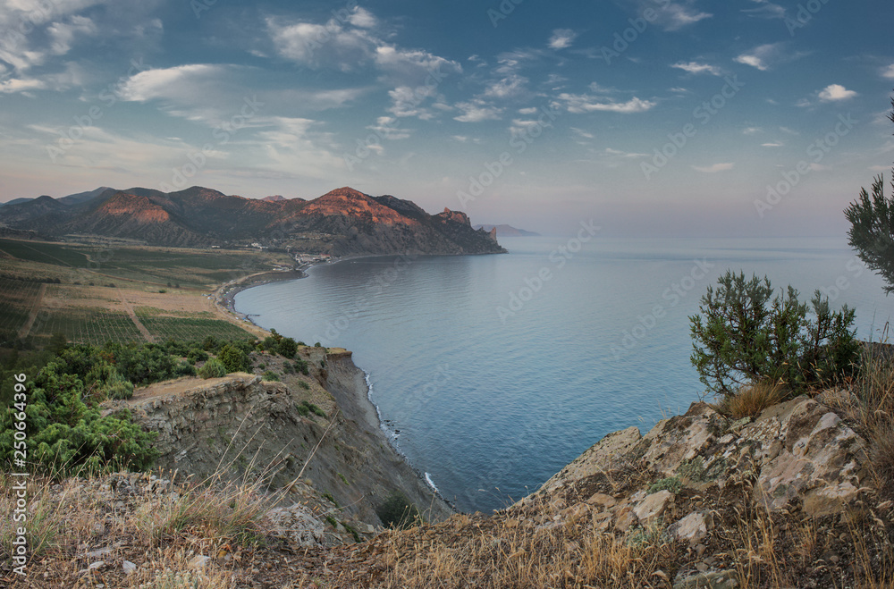  Evening twilight in a quiet bay at the foot of the mountains with vineyards. View of the southern coast of Crimea.