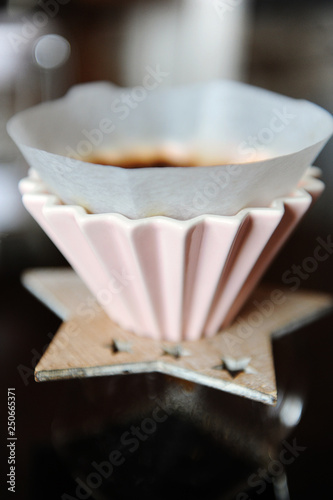 Alternative manual coffee brewing in pink ceramic dripper with paper filter. Close up photo