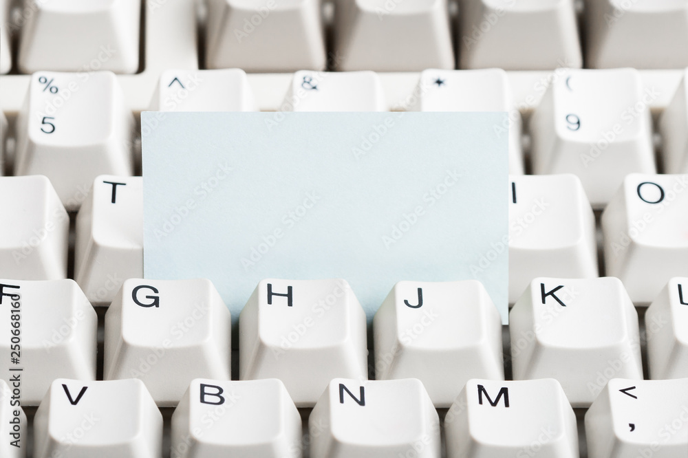 Clear paper stacked in white computer keyboard. May be used as mock up for note or message.